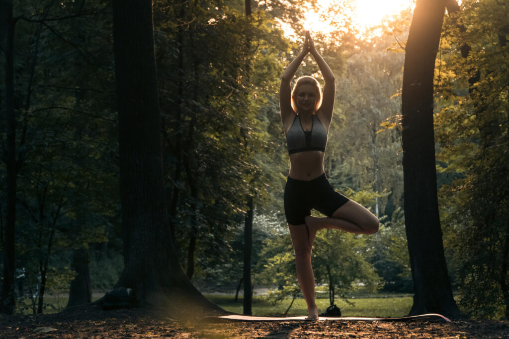 Junge Frau praktiziert Yoga im Wald