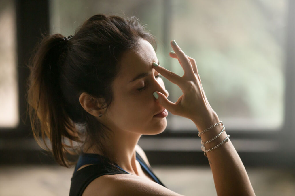 Junge Frau führt Atemübungen (Pranayama) durch