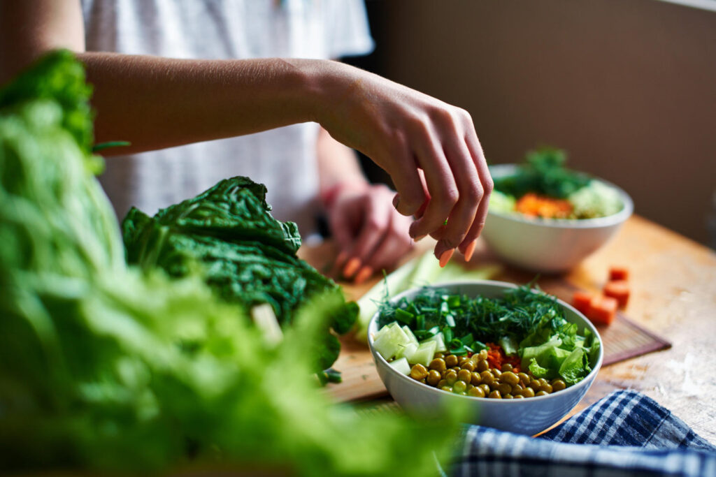 Frau bereitet einen Salat mit Longevity-Lebensmitteln vor