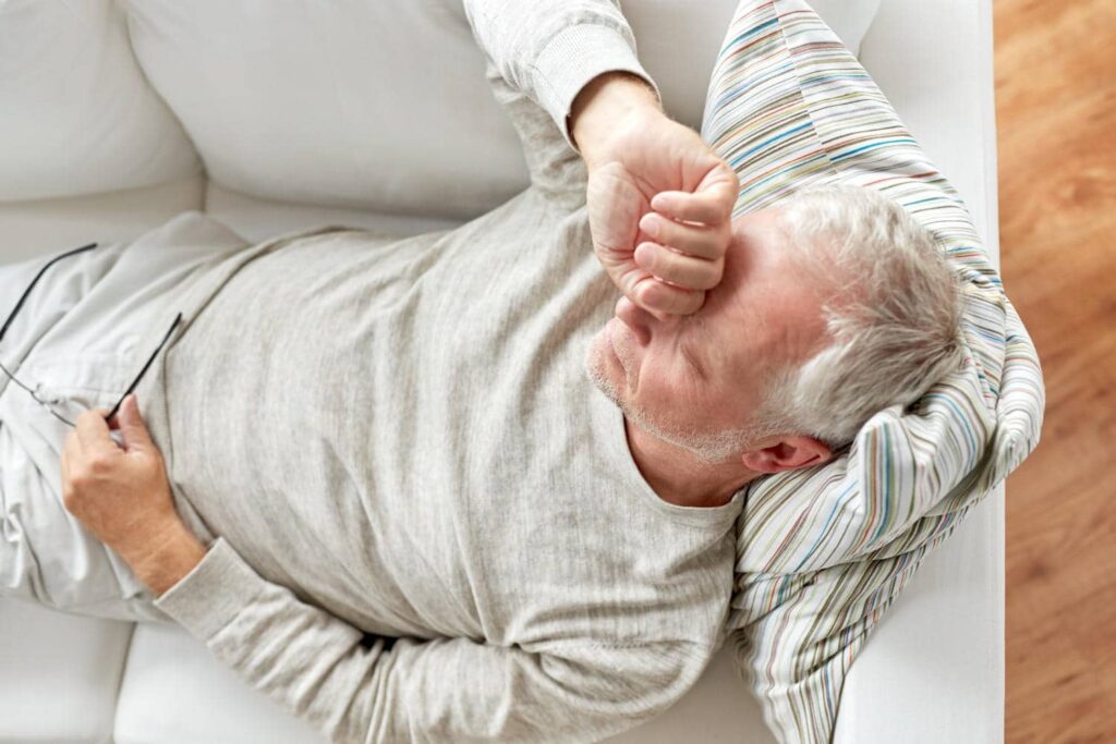 Älterer Mann liegt müde auf einem Sofa