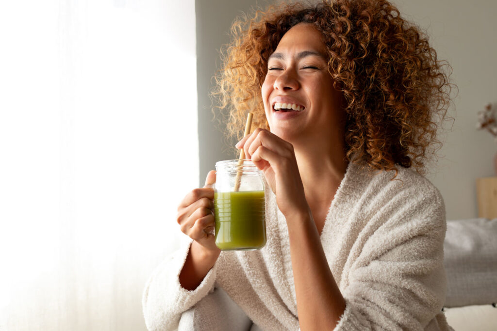 Junge Frau trinkt einen grünen Smoothie