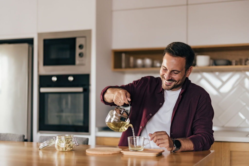 Junger Mann bereitet eine Tasse Tee zu