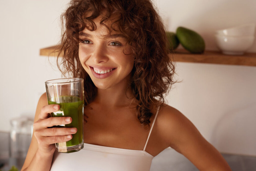 Junge Frau trinkt einen grünen Smoothie