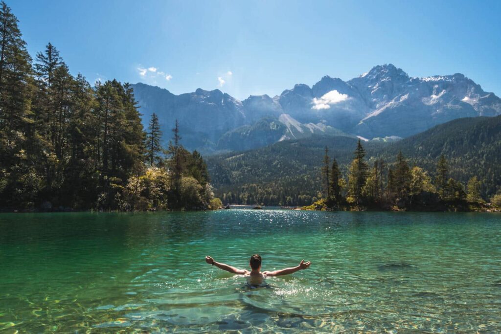 Mann schwimmt in einem Bergsee
