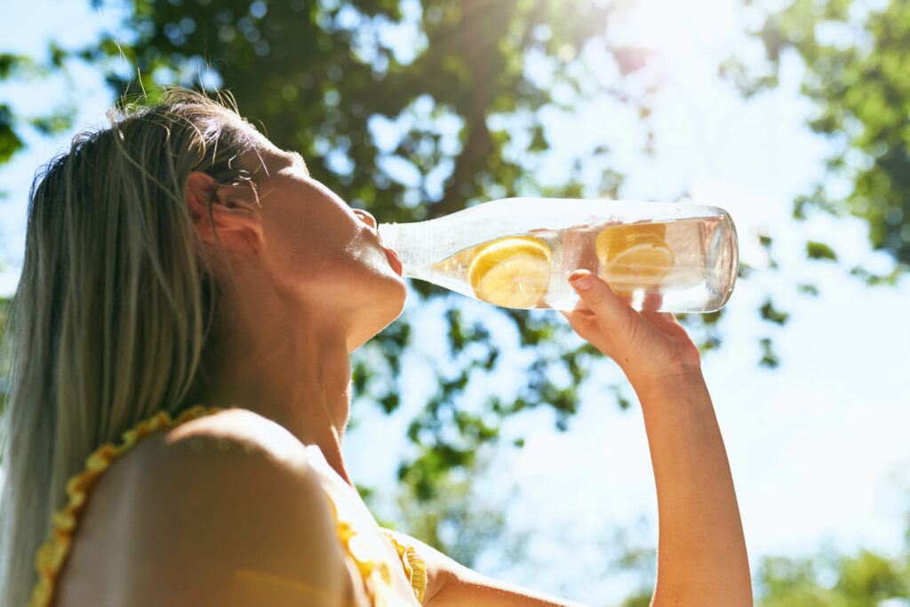 Frau trinkt Wasser mit Zitrone
